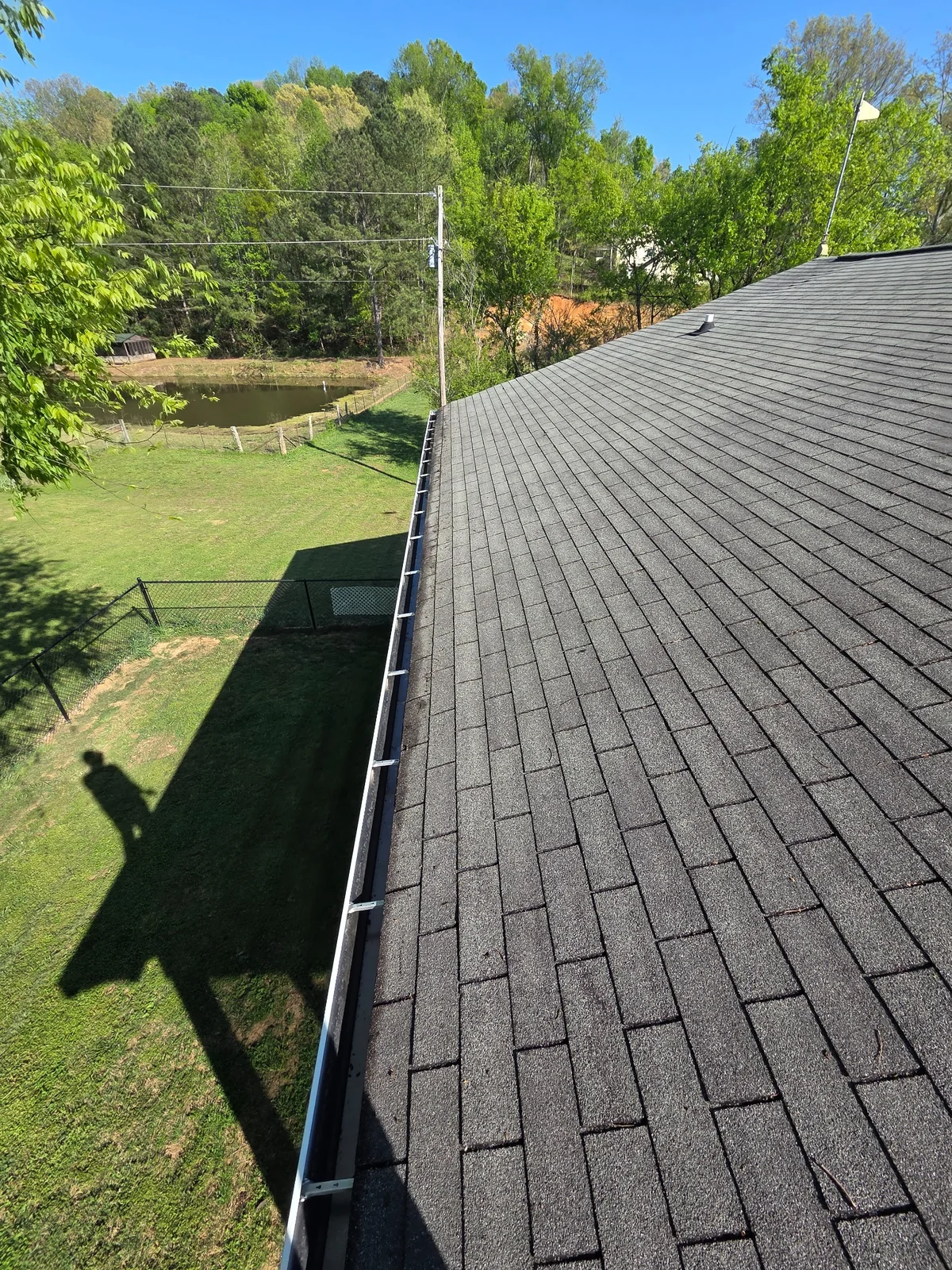 Gutter alongside a shingled roof during maintenance