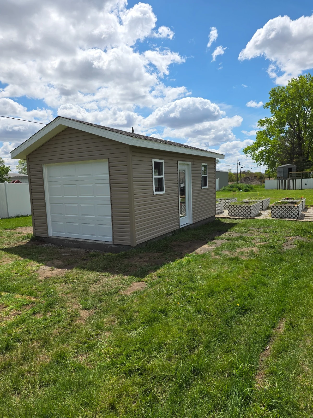 Completed detached outbuilding with siding and overhead door